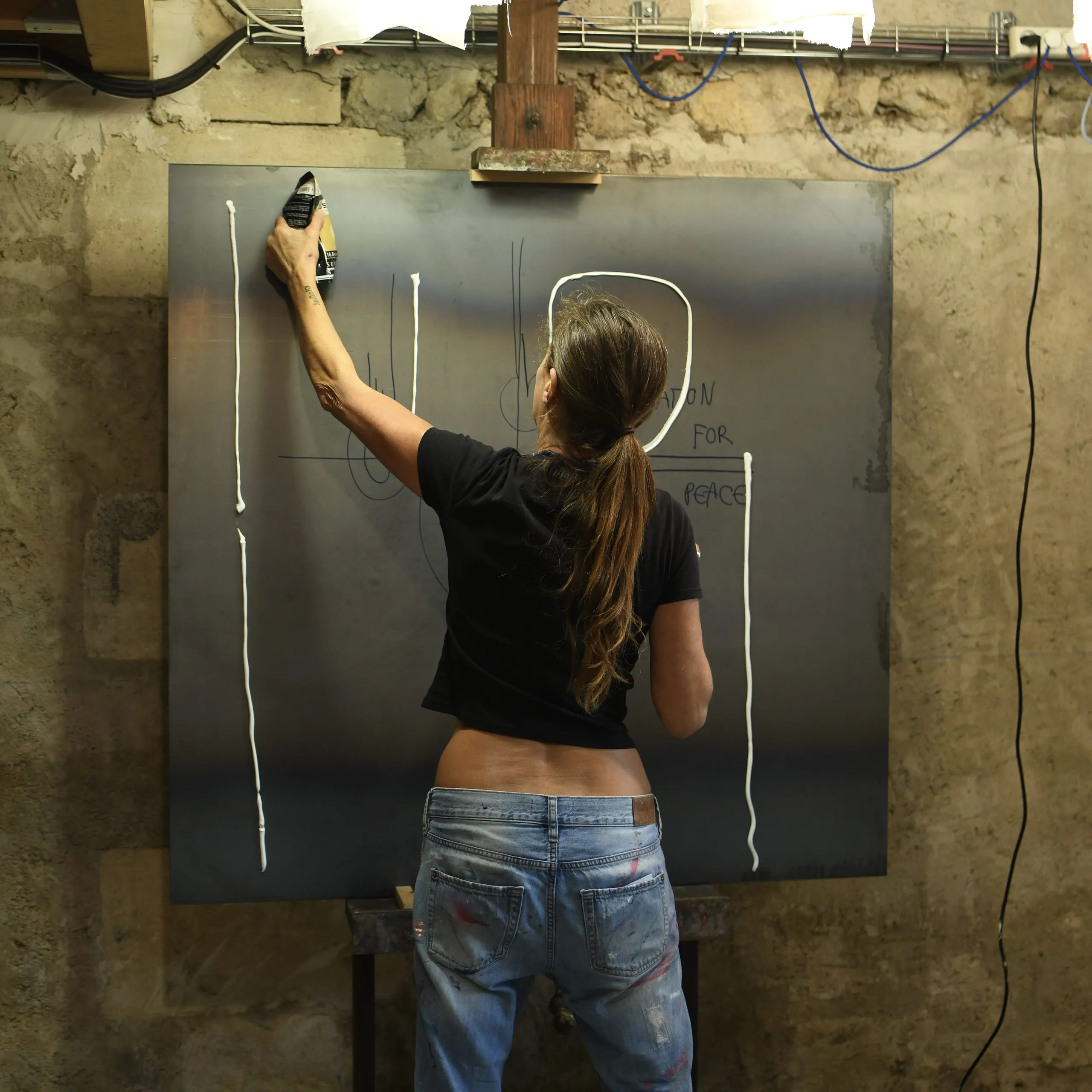 Véronique Massie drawing symbols on a metal plate